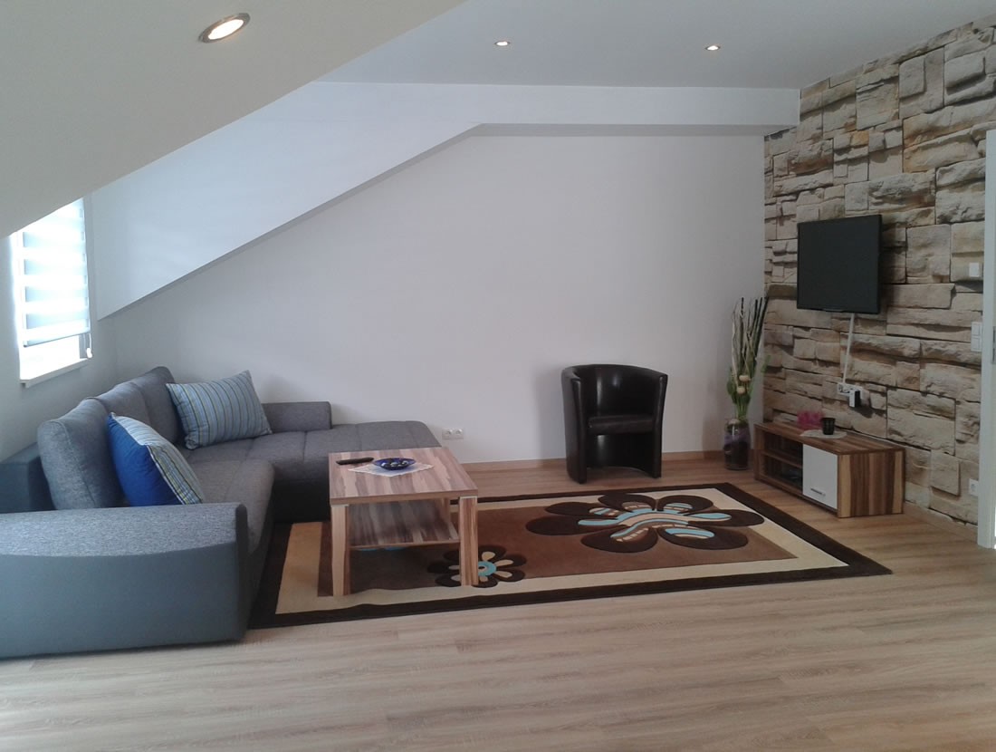 Wohnzimmer mit großer Couch und Flat-TV