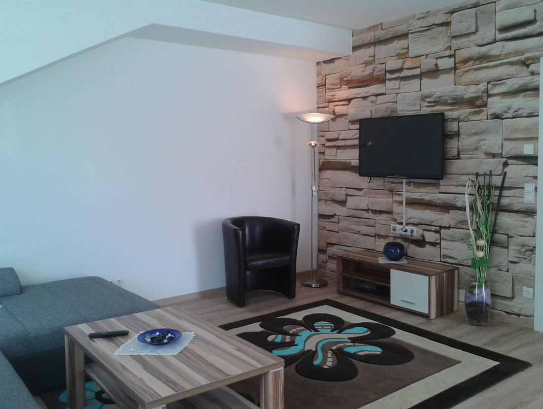 Wohnzimmer mit großer Couch und Flat-TV